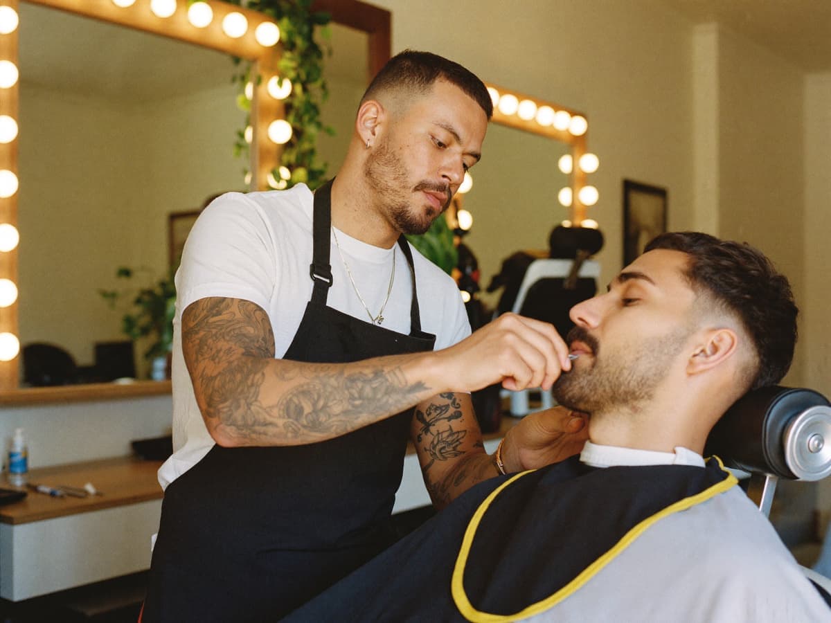 Barbero recorta la barba de un cliente en una barbería moderna