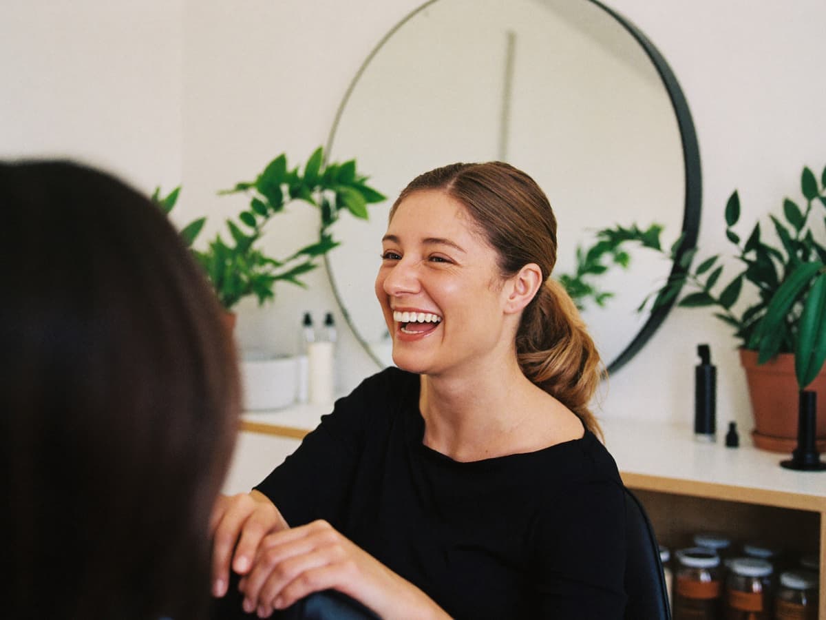 Dueña de un salón de belleza platica y ríe con una clienta